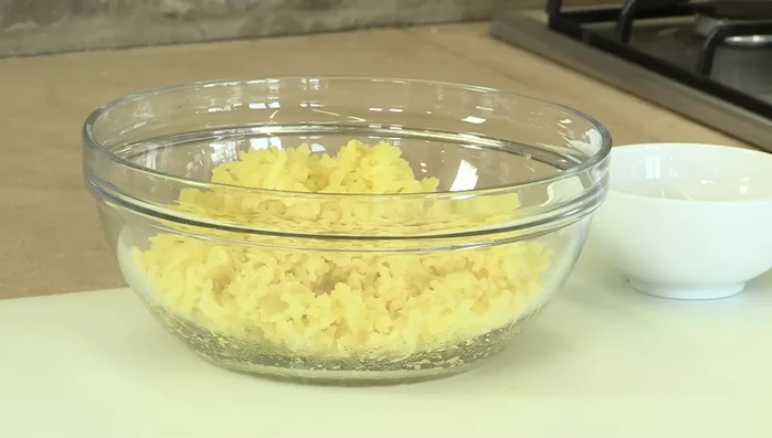 Lessare le patate al vapore, quindi farle raffreddare e schiacciarle. È importante che siano fredde per eliminare l'umidità in eccesso.
